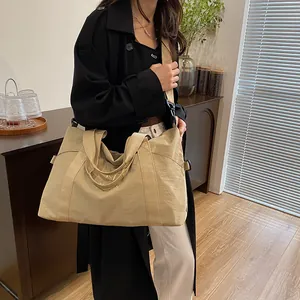 Dettaglio borsa da viaggio beige con ricamo M, cinghie larghe e trama in nylon