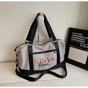 Detail of grey and black travel bag hanging on a rack showing waterproof nylon and zip pocket