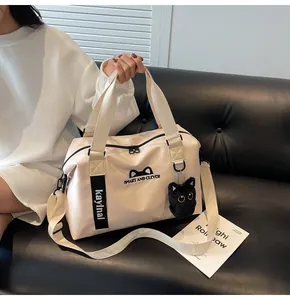Detail of travel bag with plush cat charm and adjustable strap on a leather sofa