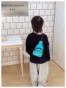 Sac bandoulière bleu pour garçons avec lettres blanches porté par un modèle en intérieur