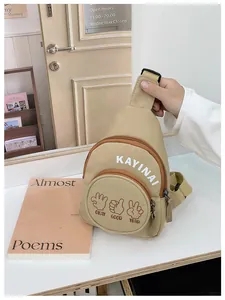 Detail of beige canvas kids crossbody chest bag with adjustable strap and graphic prints