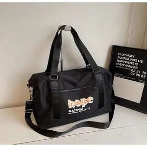 Front detail of black travel bag with sturdy handles and adjustable shoulder strap