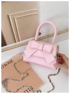 Detail van de roze handtas met strik, voorzien van metalen ketting en ronde greep