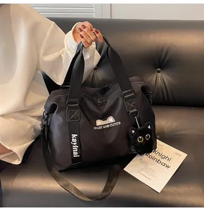 Detail of black nylon travel bag featuring cat embroidery and cute plush cat keychain
