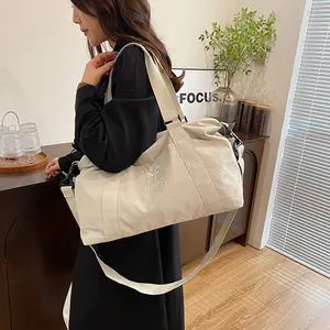 Dettaglio di una borsa da viaggio grande in nylon bianco panna con tracolla e logo