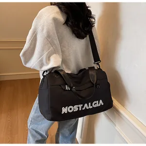 Detail of black canvas travel bag featuring white NOSTALGIA lettering and striped straps