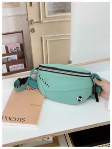 Detail van de muntgroene crossbodytas met nylon textuur en zwarte merkbelettering