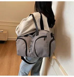 Vista dettagliata della borsa sportiva grigia versatile con ampia tracolla nera e scritte
