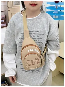 Close-up of khaki canvas kids chest bag featuring dual zippers and graphic letter prints