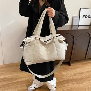 Borsa da viaggio beige minimalista con tracolla regolabile su modella in interno di classe