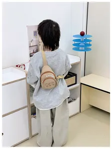 Kids khaki canvas crossbody bag with letter print shown on model for back view effect
