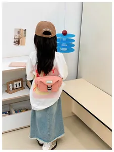 Pink crossbody bag for kids with black buckle and adjustable strap on a young girl
