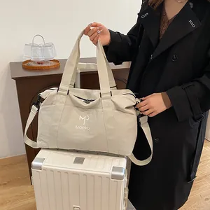 Dettaglio della borsa da viaggio beige sulla valigia con logo MP e tracolla