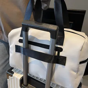 Detail van grote witte reistas met zwarte bagageriem bevestigd aan een kofferstang