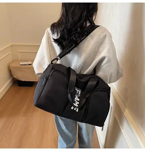 Dettaglio della borsa sportiva nera con scritte bianche e tracolla regolabile sulla modella
