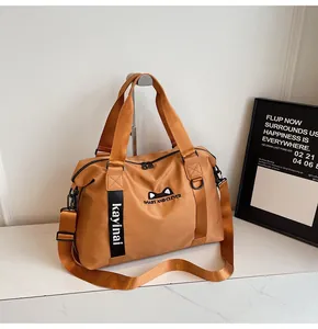 Detail of camel travel bag showing cat ear logo embroidery and adjustable shoulder strap