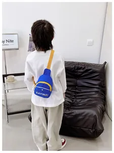 Détail du sac bandoulière en nylon bleu avec zips jaunes et lettrage blanc sur modèle