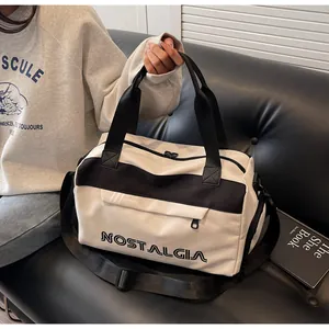 Detail of travel duffel bag showing NOSTALGIA letter print and crossbody strap