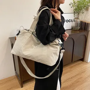 Dettaglio della borsa da viaggio bianco sporco con tracolla regolabile e logo ricamato