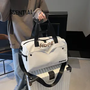 Close-up van witte sporttas met zwarte handvatten op een witte koffer