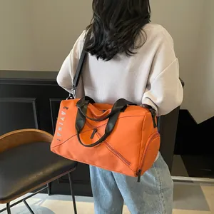 Detalle de bolsa de deporte naranja con correa de hombro y bolsillo lateral