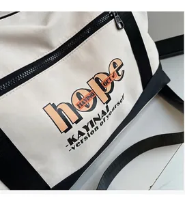 Detail van canvas tas met hope-print en zwarte riem met een stevige ritssluiting