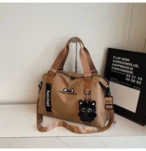 Close-up of khaki nylon travel bag with cute cat embroidery and plush pendant charm