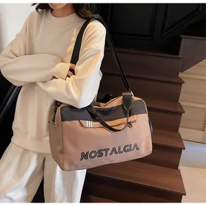 Detail of a khaki travel bag with black straps and NOSTALGIA lettering on wooden stairs