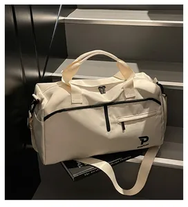 Detalle del bolso deportivo crema con cremalleras negras sobre un libro de diseño