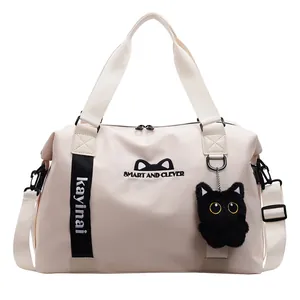 Detail of cute cat embroidery and plush kitten charm on large cream travel bag