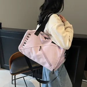 Bolso de viaje rosa con correas negras y logo de marca llevado por una modelo