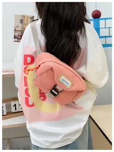 Pink canvas crossbody bag featuring adjustable beige strap and branding on the back