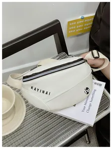 Detailopname van een witte crossbody heuptas met zwarte rits en branding op een bank