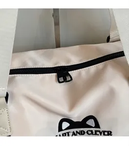 Detail of smooth two-way black metal zippers on off-white nylon travel bag with embroidery