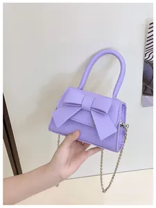 Detailopname van een lila handtas met strik, metalen kettingriem en rond handvat