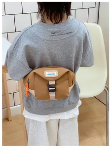 Detail view of brown canvas belt bag showing adjustable beige strap and brand patch