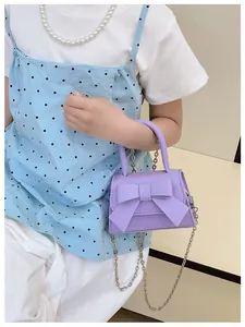 Gedetailleerde opname van een lila crossbodytas met een grote strik en zilveren ketting