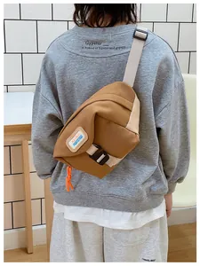 Detailed view of brown canvas waist bag with adjustable strap and orange drawstring detail
