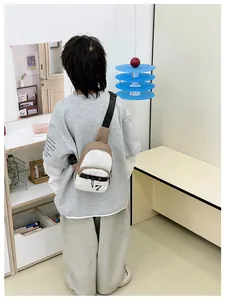 Back view of the beige and white crossbody chest bag shown on model in a minimalist room