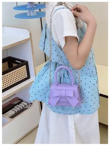Detail van paarse mini crossbodytas met grote strik en zilveren kettingriem voor dames