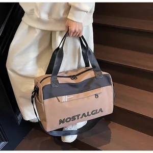 Large khaki travel duffel bag with black straps and adjustable shoulder strap on stairs