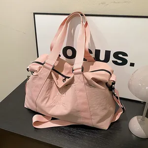 Dettaglio della borsa sportiva in nylon rosa con ricamo del brand e tracolla regolabile
