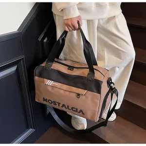 Brown and black travel bag with double webbing handles and adjustable strap in use