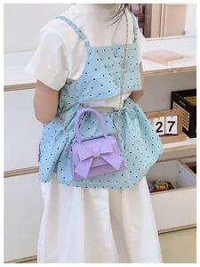 Close-up van een lila mini-tas met strik en zilveren ketting gedragen door model