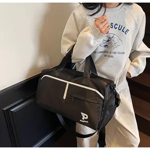 Bolso deportivo negro impermeable con detalles blancos y asas llevado por una modelo