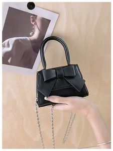 Detailopname van zwarte mini-tas met grote strik en zilveren kettingriem voor dames