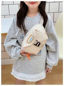 Close-up of cream canvas chest bag with decorative label and orange zipper pull detail
