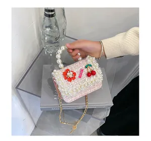 Détail d'un sac fille en tweed rose avec poignée en perles et bandoulière en chaîne