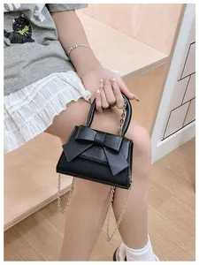 Detailopname van een zwarte mini handtas met strik van PU-leer en een zilveren ketting