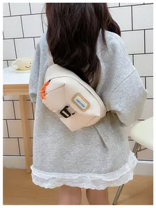 Close-up of children beige chest bag with brown leather label and orange zipper detail